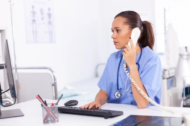 medical-nurse-talking-with-patient-phone-about-diagnosis-health-care-physician-sitting-desk-using-computer-modern-clinic-looking-monitor